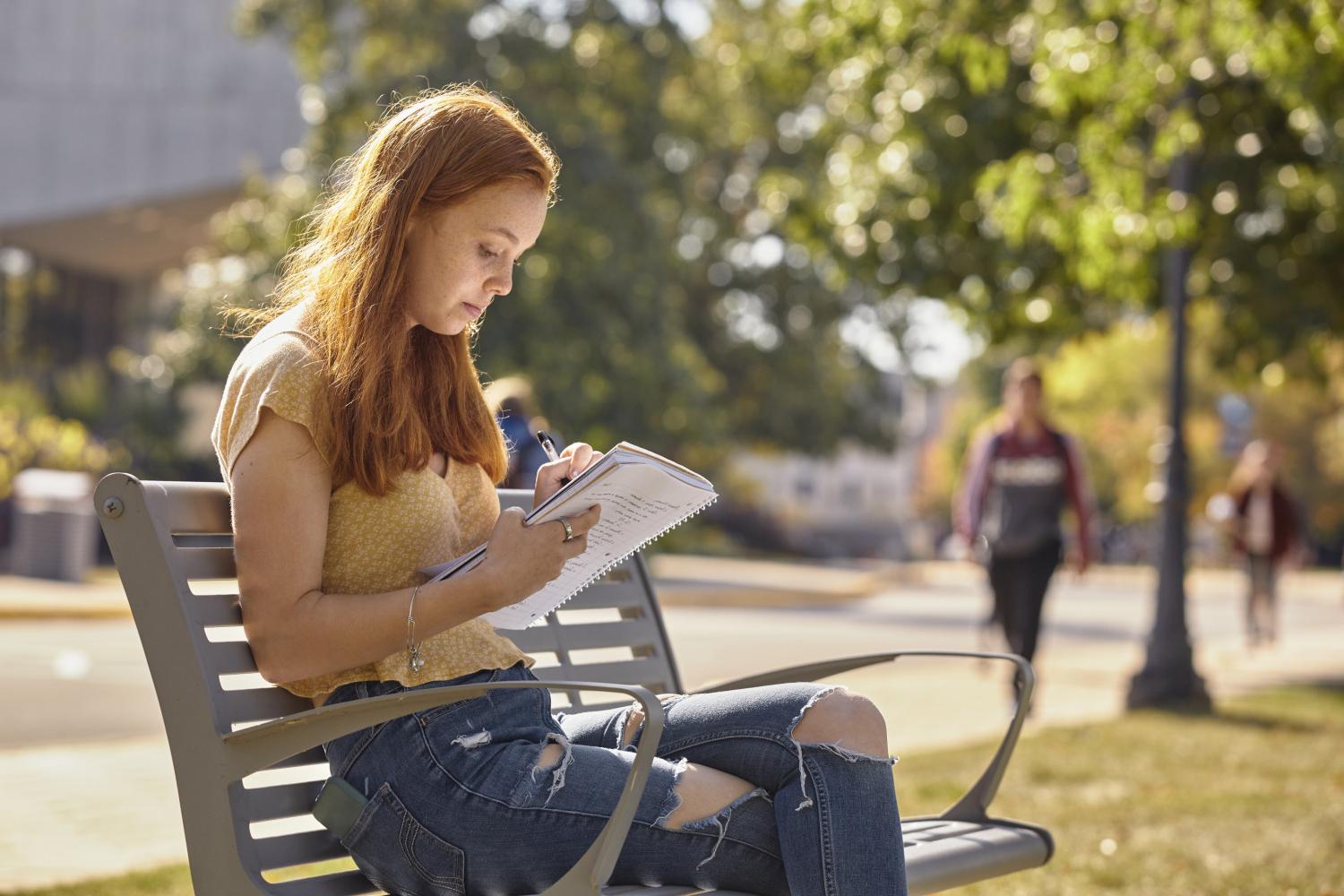 A <a href='http://jfllem.femdomcenter.com'>全球十大赌钱排行app</a> student reads on a bench along Campus Drive.